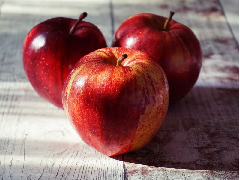 three red apples on wooden floor