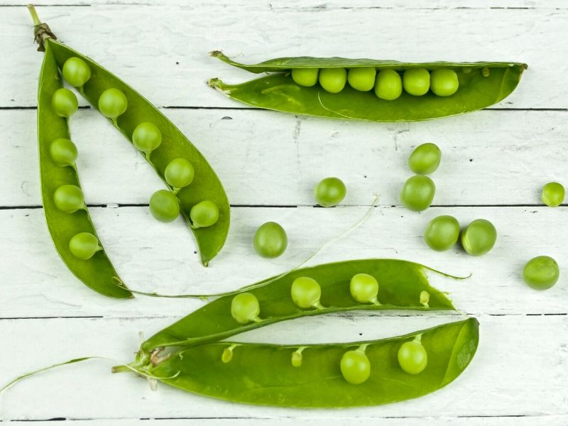 green peas on white wooden floor, baby first solid food