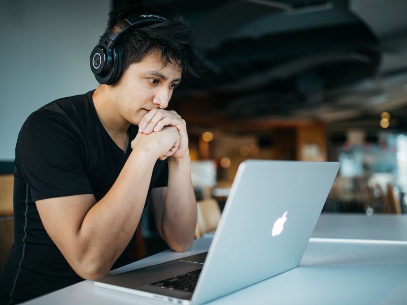 a man with headphones on watching content on a laptop