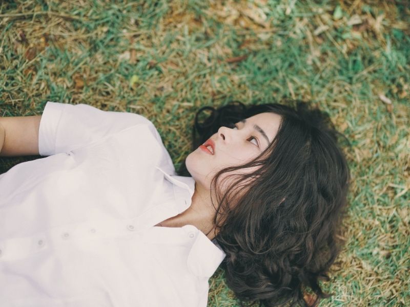 woman with curly hair lying on the grass