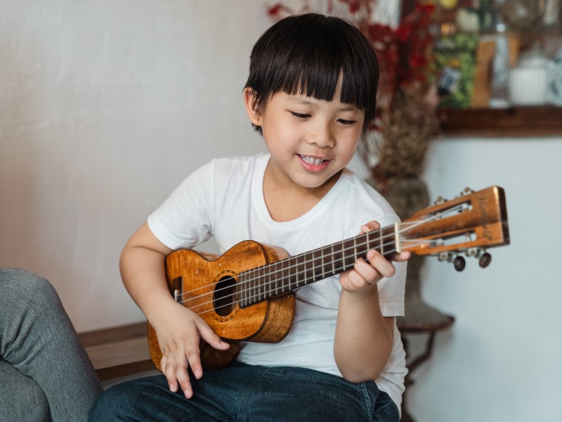 asian kid playing the ukulele kids indoor activities