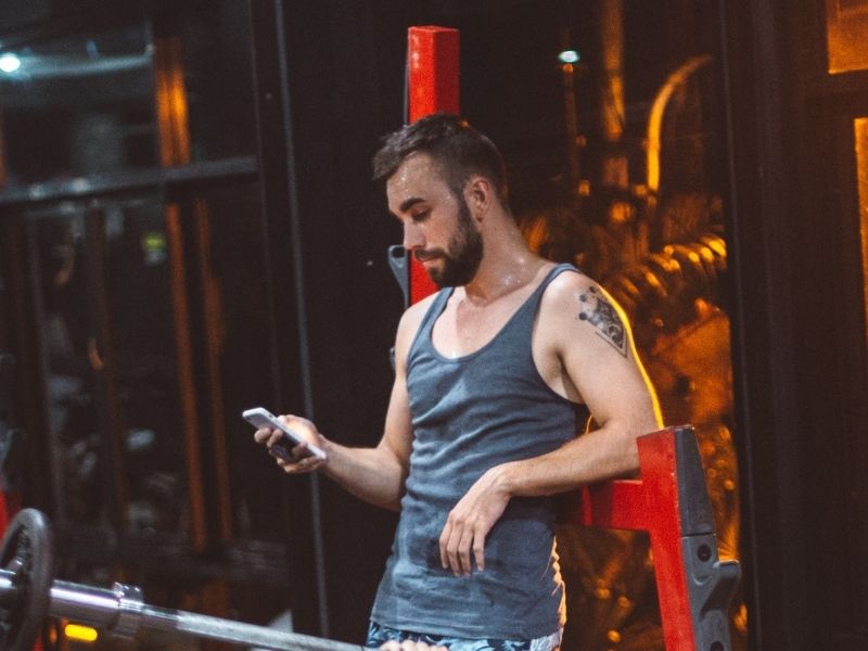 man at gym looking at phone