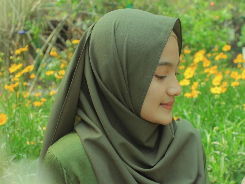 woman wearing green hijab in a field of flowers