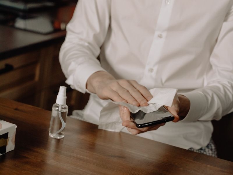 person cleaning a smartphone how to sanitize phone