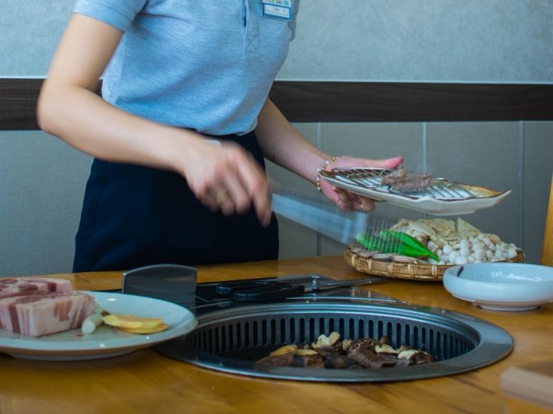 waitress grilling meat