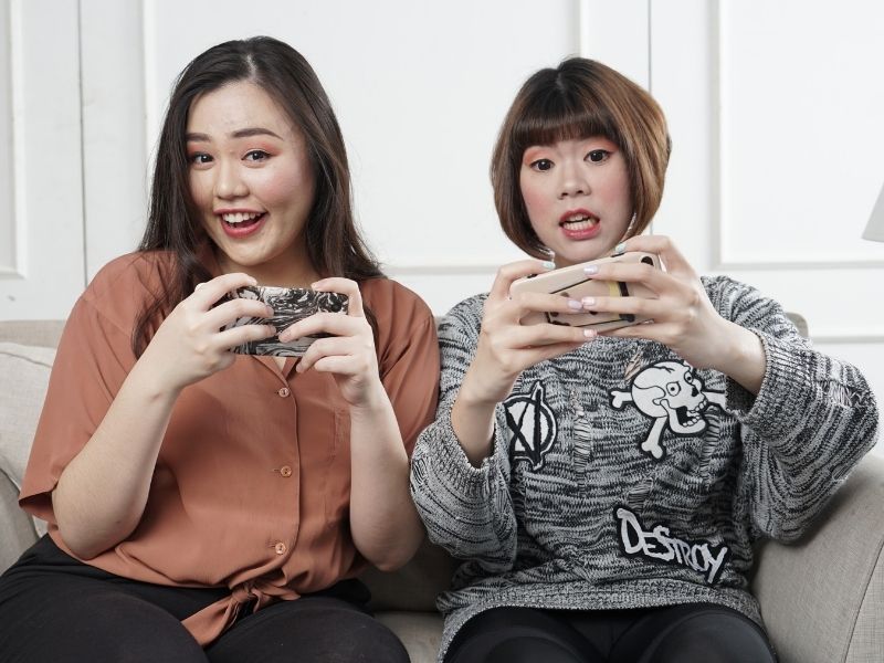 Two women playing video games on a couch