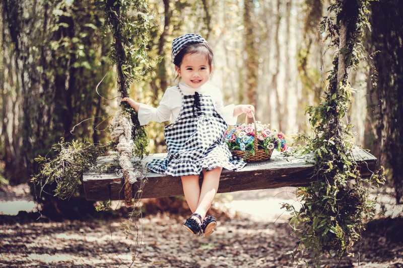 popular girl names, little girl sitting on swing in garden