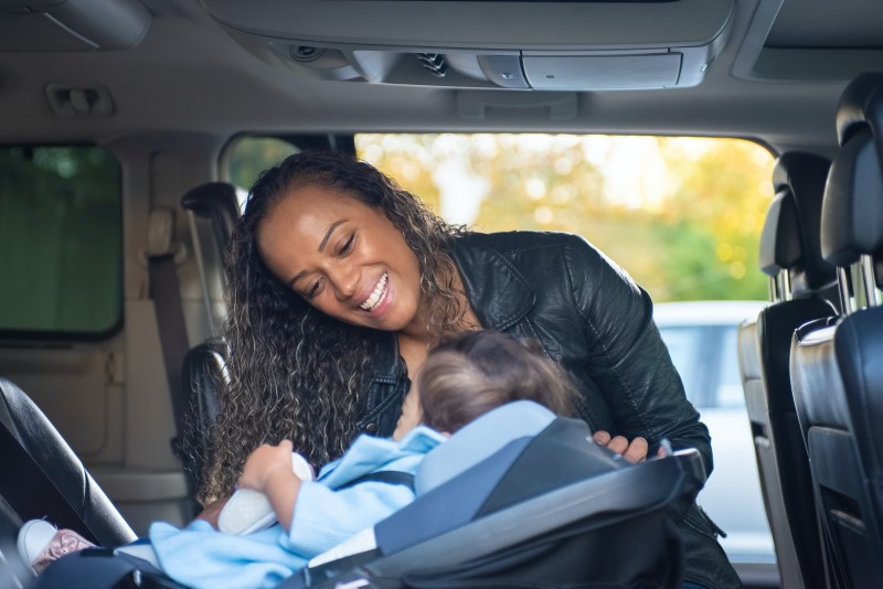 mother putting baby in car seat 