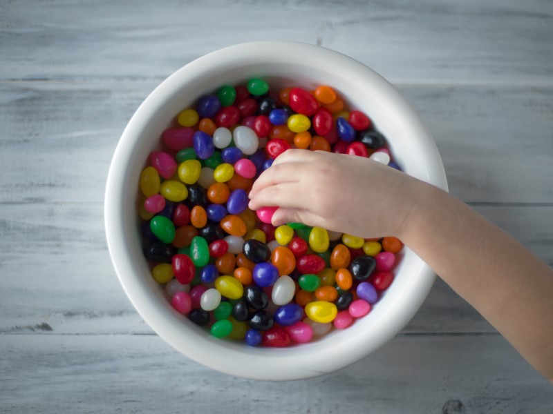 kid reaching for jelly beans in bowl