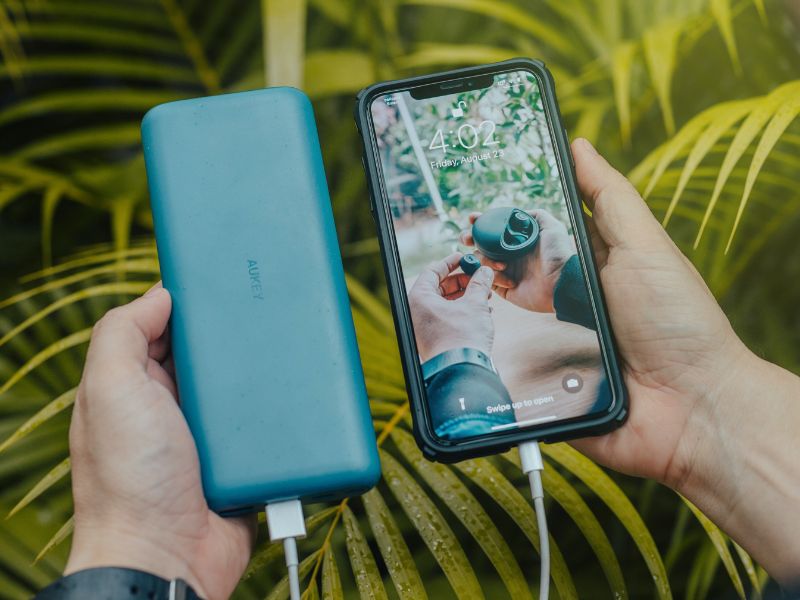 a person holding a smartphone and a power bank