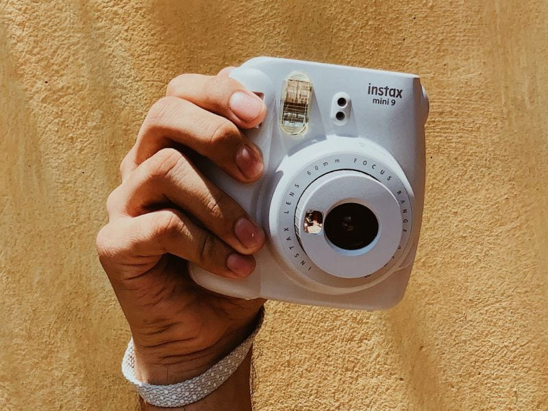 a person holding a Fujifilm Instax camera