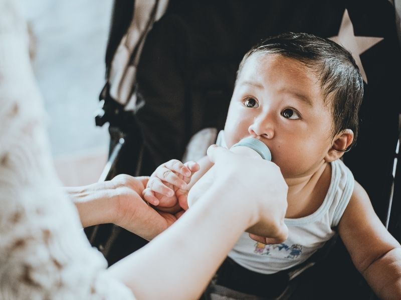 a baby being fed milk in a bottle