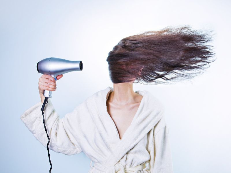 a woman blow drying her hair