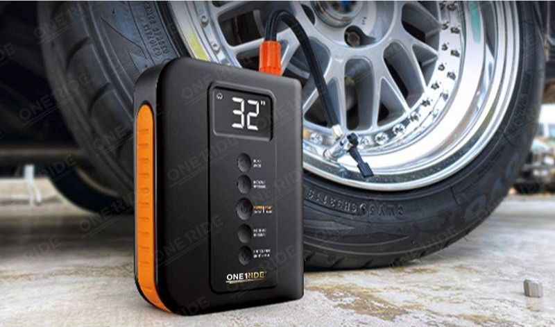 A jump starter power bank beside a car wheel