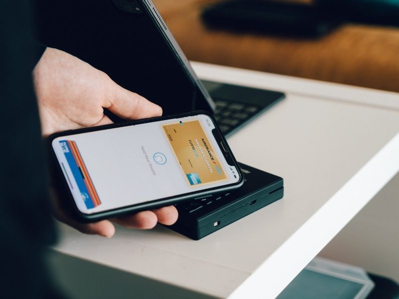 a person holding their phone near a terminal to make a payment