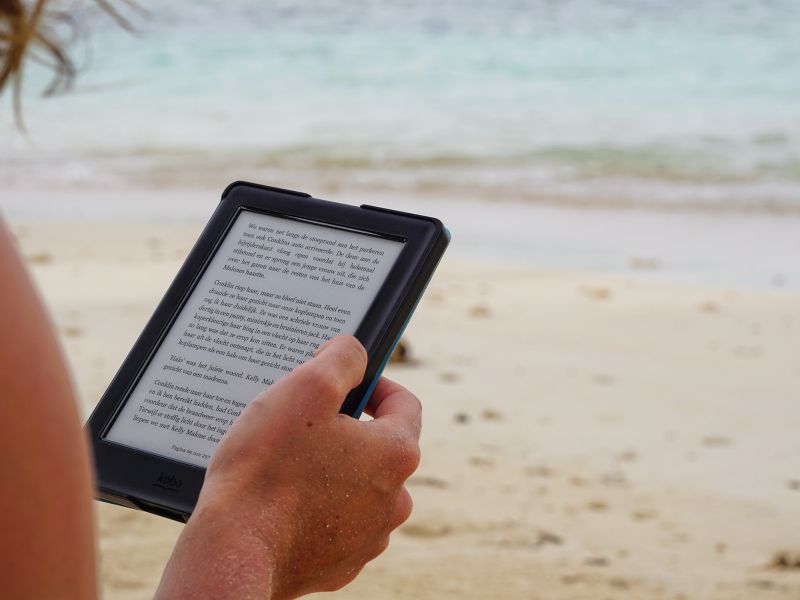 A person reading with an ebook reader by the beach