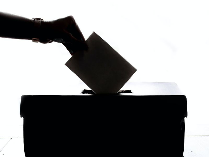 A hand putting a ballot paper into a ballot box