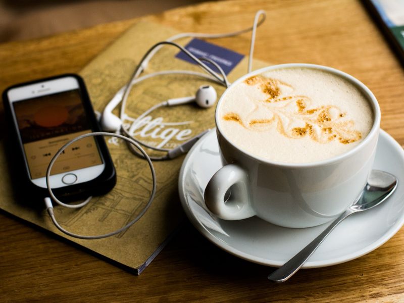 A smartphone, a notebook, and a cup of coffee on a table