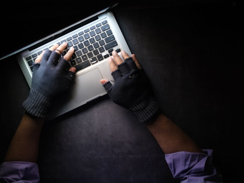 a pair of hands in glove using a laptop
