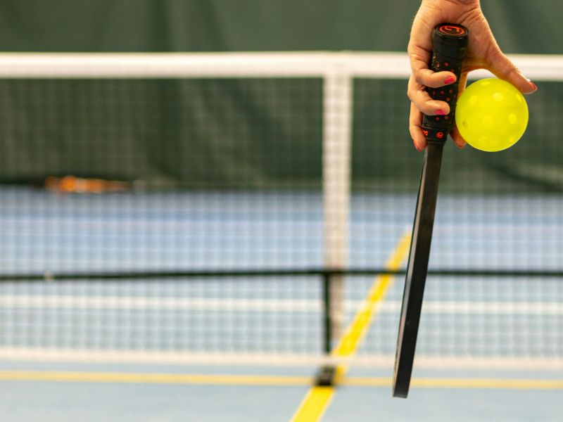 a person holding a paddle and pickleball