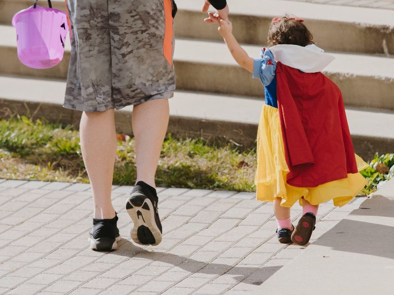 a woman holding a kid's hand while walking 