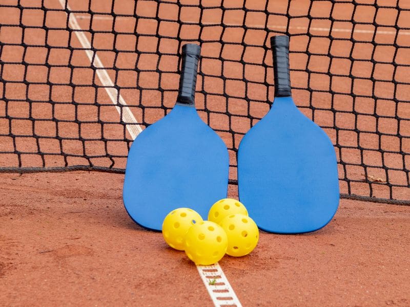 Paddles and pickleballs on a court pickleball courts kl