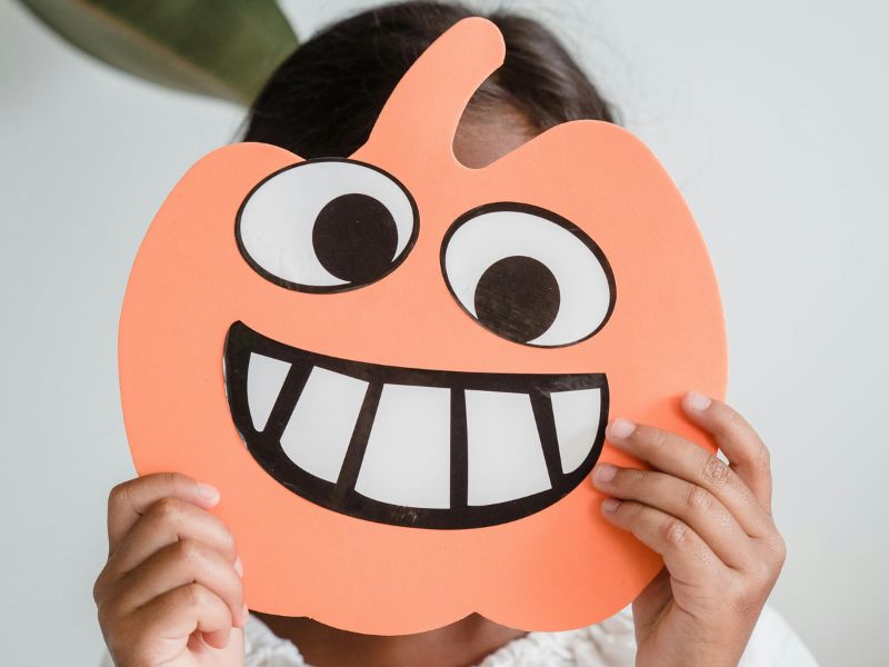 a kid holding a smiley face mask topeng muka