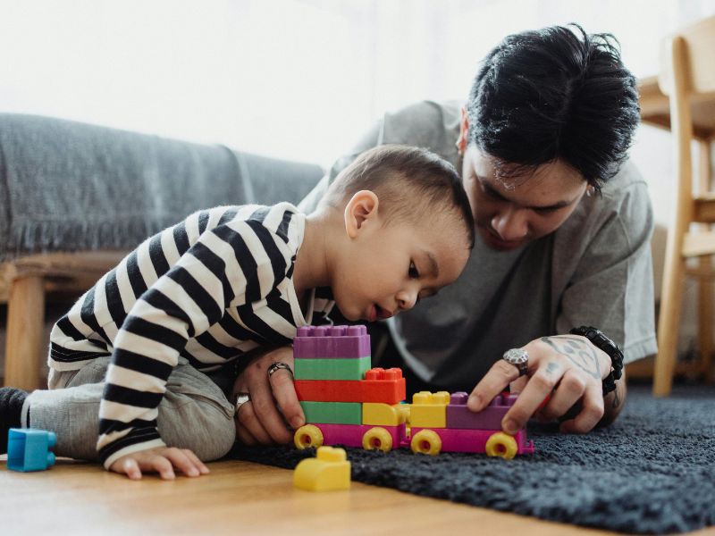 an adult and a kid playing toys together kereta mainan