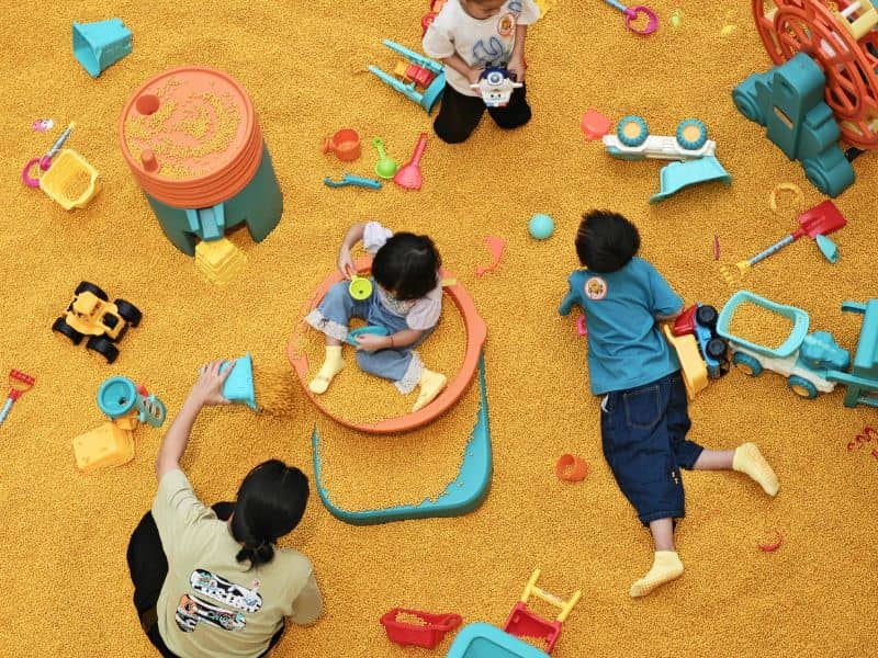 adult and kids playing on a sand surface kereta mainan